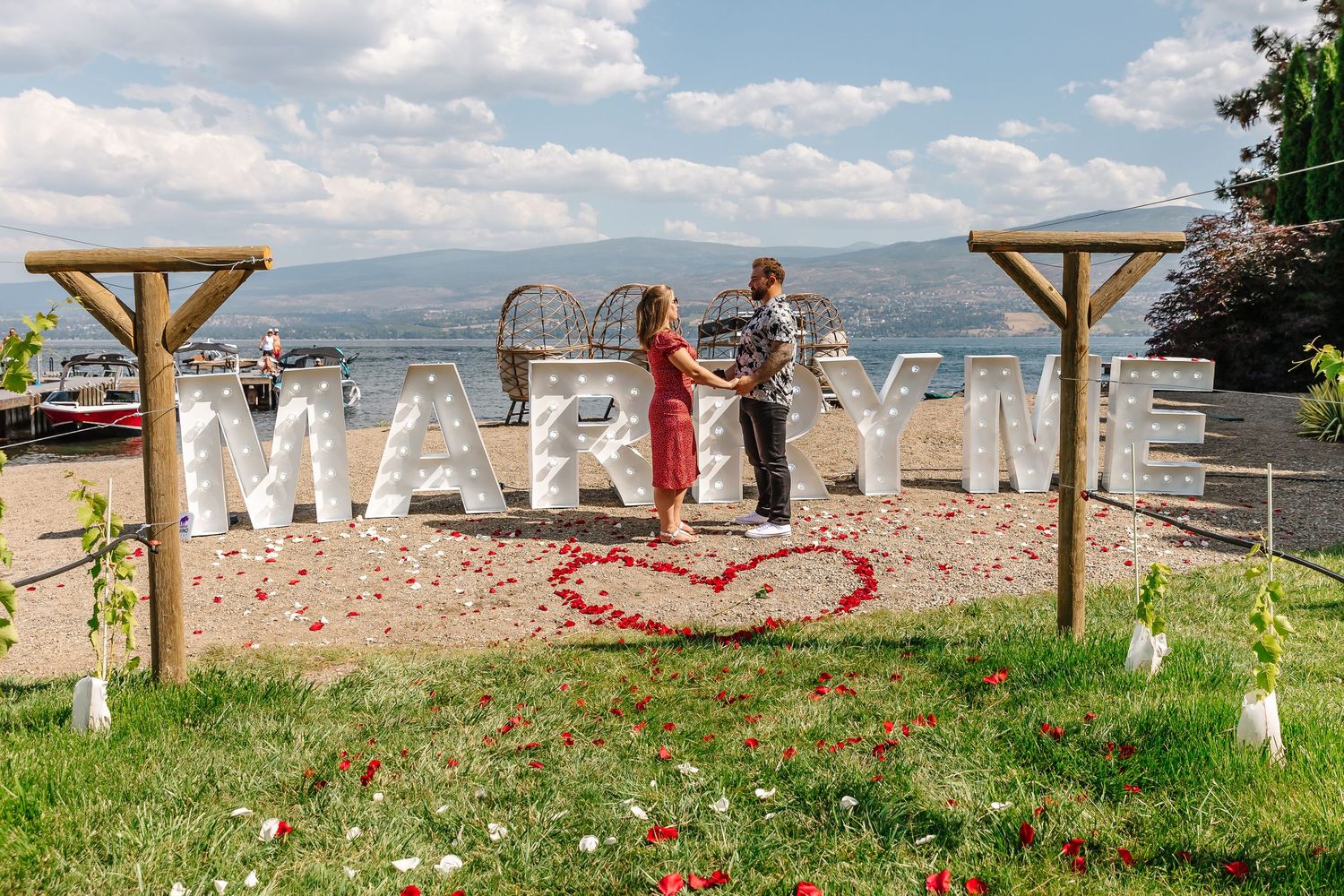 Large white marquee letters spell out MARRY ME at frind winery in west kelowna for surprise photography photoshoot on the beach with lake