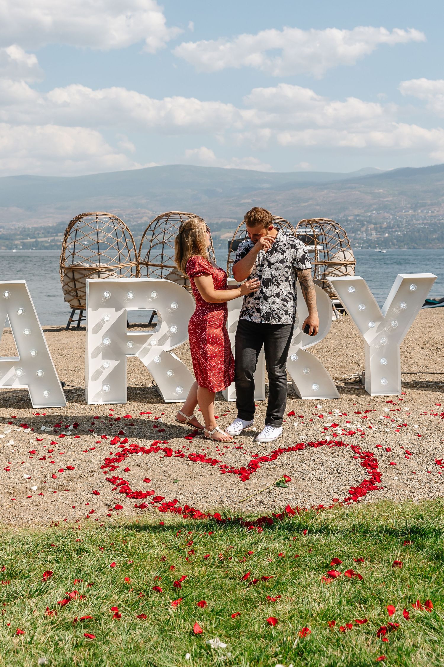 Large white marquee letters spell out MARRY ME at frind winery in west kelowna for surprise photography photoshoot on the beach