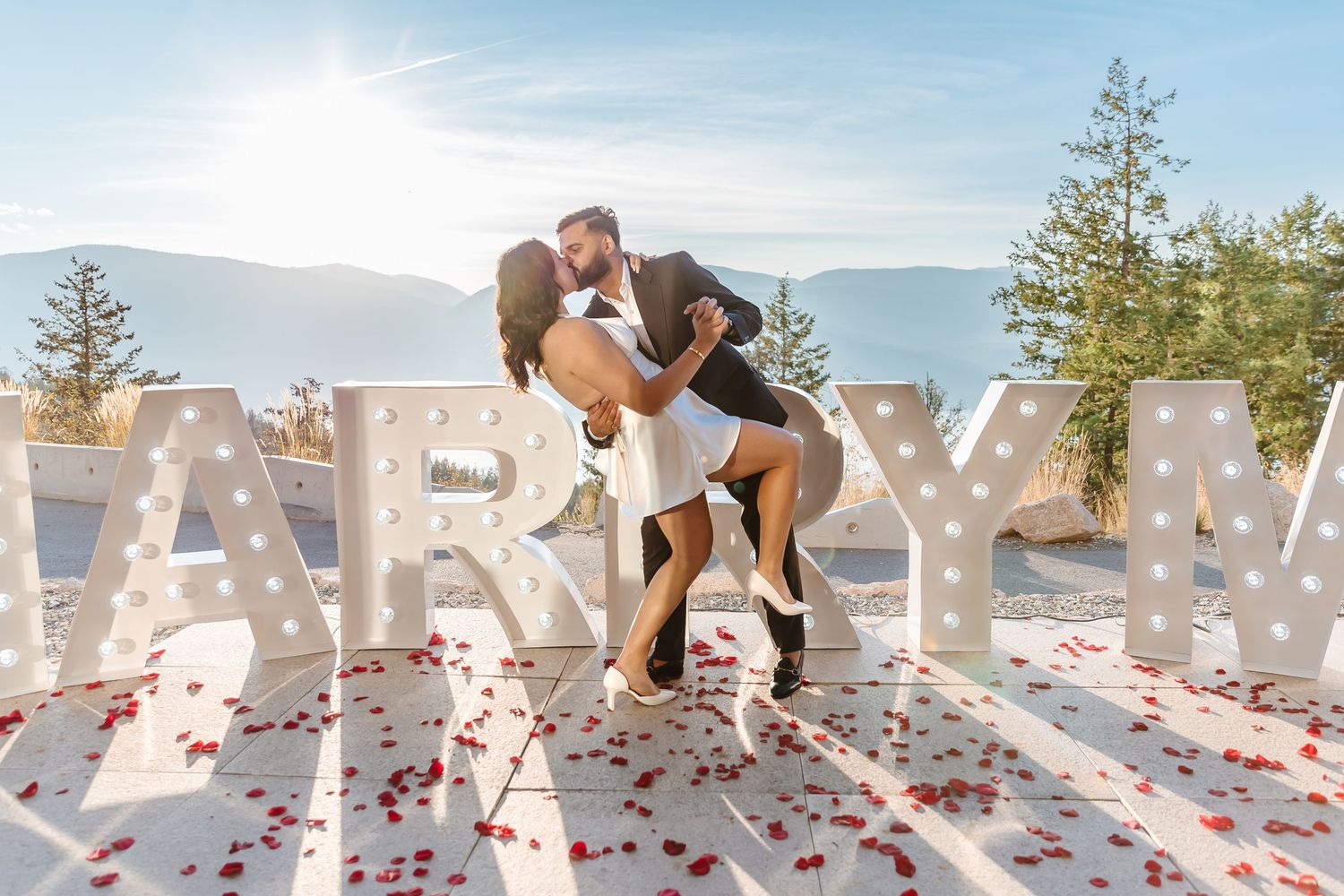 surprise proposal photoshoot at sparkling hills resort with white marquee letter sign that spells MARRY ME in Kelowna bc at sunset