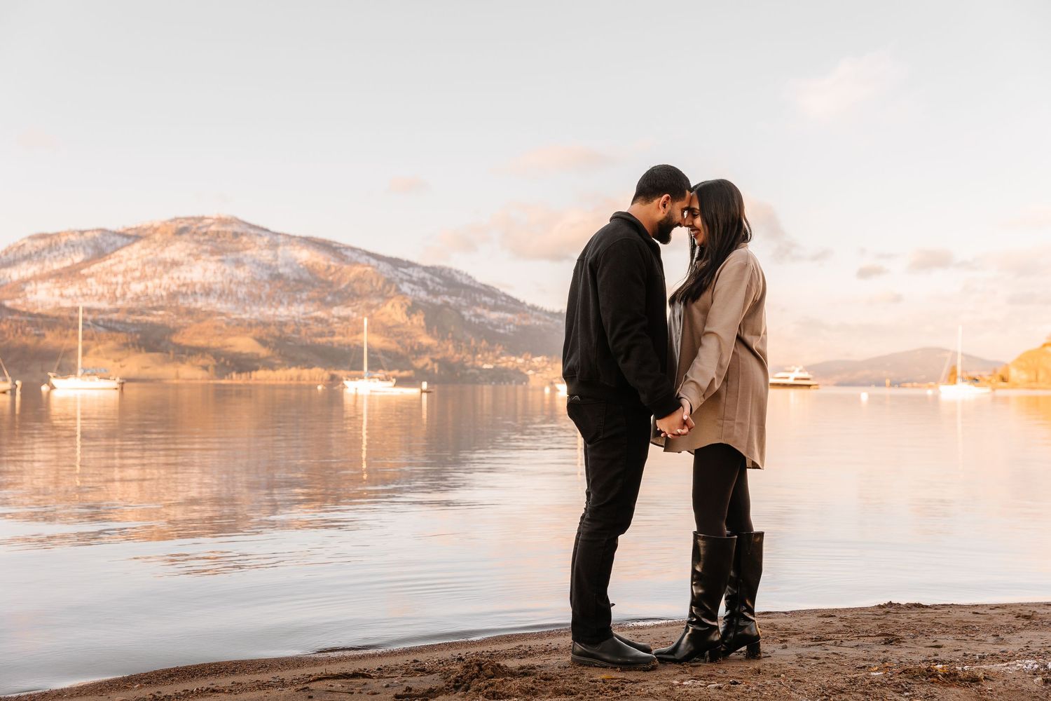 A couple shares a romantic moment during sunset by Okanagan lake for a surprise proposal engagement photoshoot