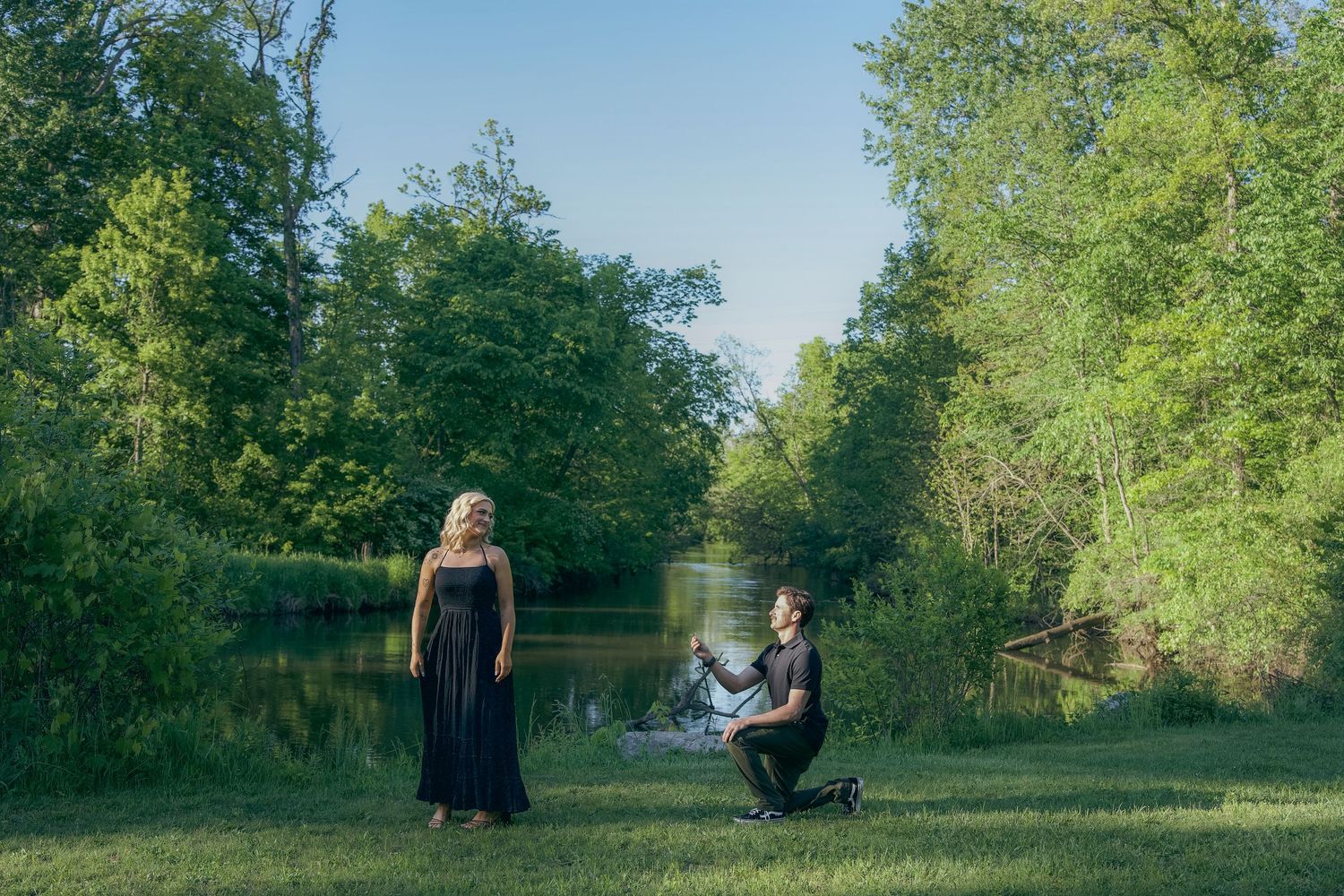 A couple poses together in a lush green park setting during a spring outdoor photo session.