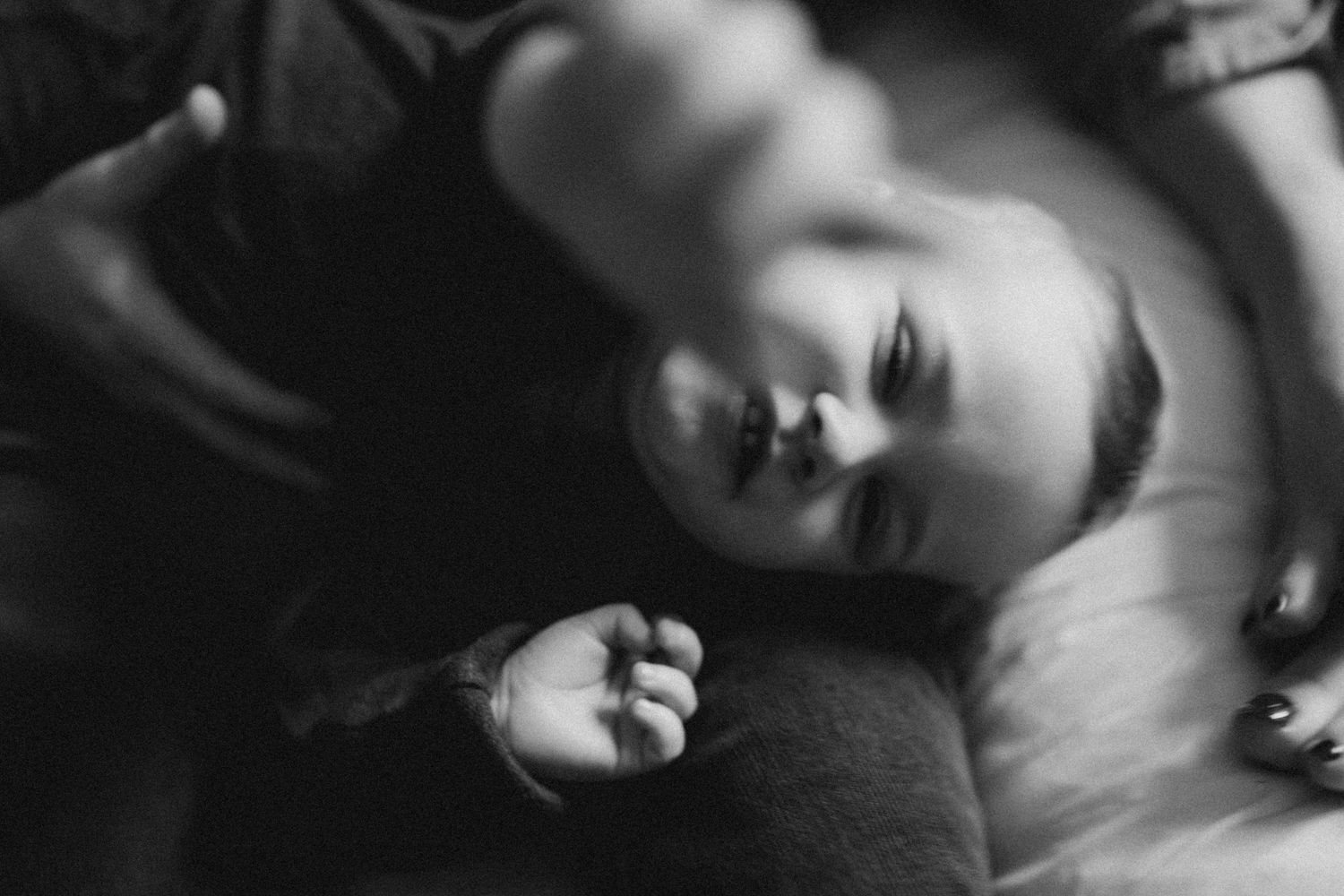 a baby lying on the bed looks up to the camera and tried to touch the lens