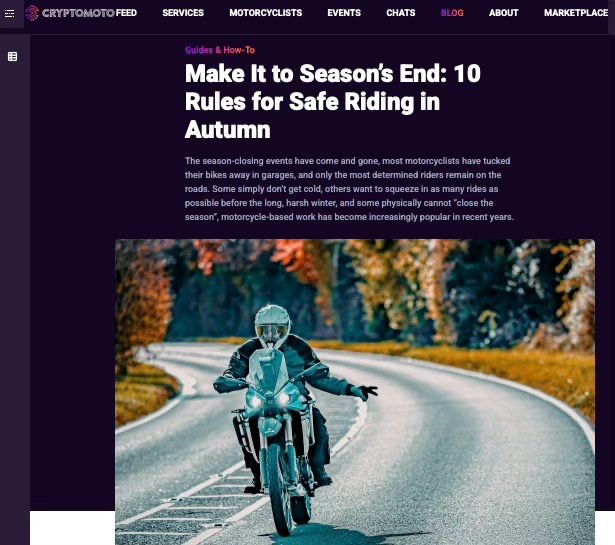 Motorcyclist in teal riding gear navigates a curved road during autumn with colorful foliage in the background.
