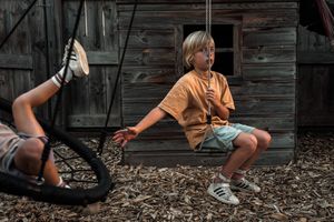 Kids playing with toys in mulch near a rustic wooden structure.