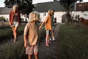 People walk through tall grass in a field during golden hour.