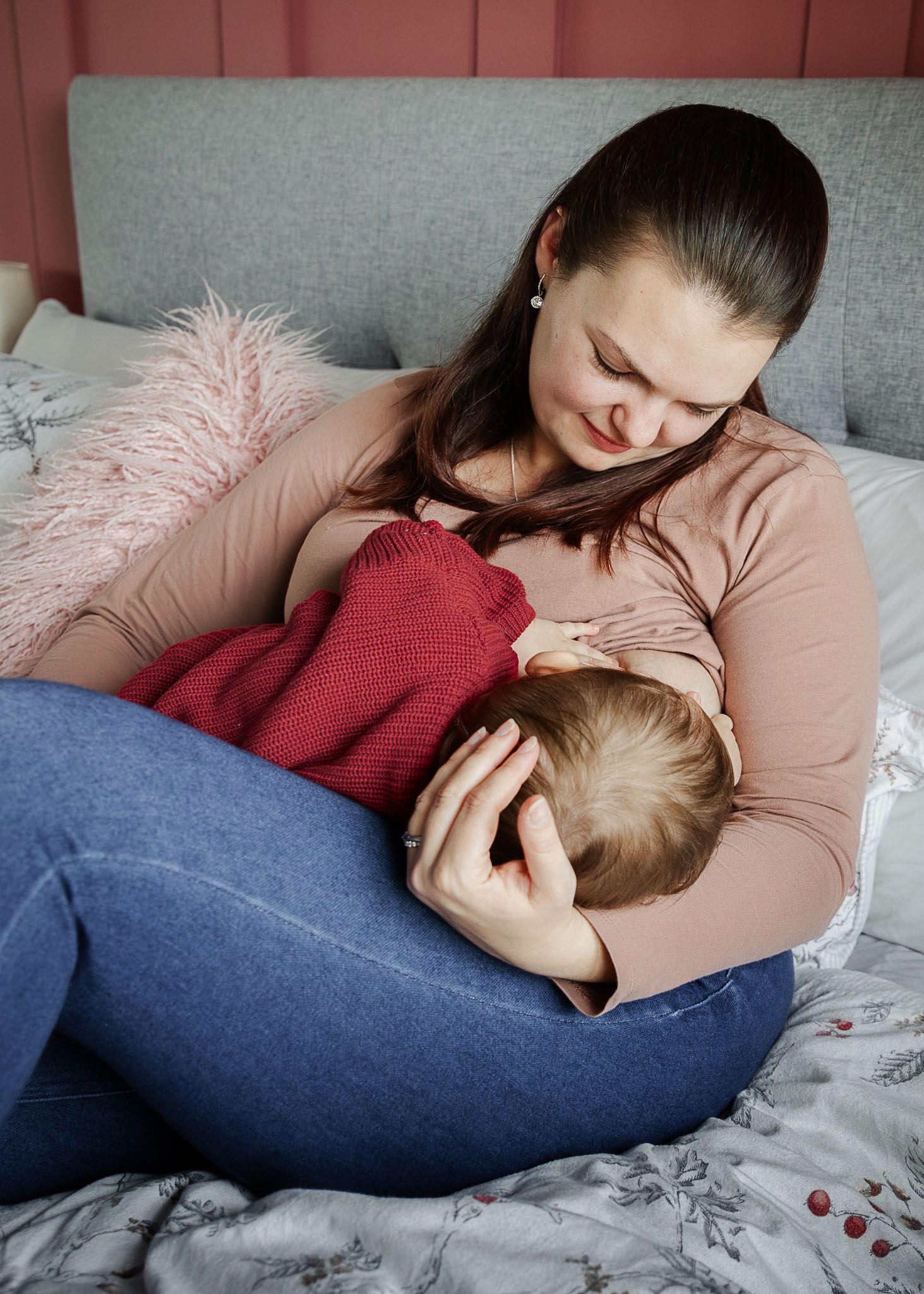 A mum sits quietly on her bed at home and looks lovingly at her toddler as she breastfeeds him. Relaxed Bristol baby in home photographer
