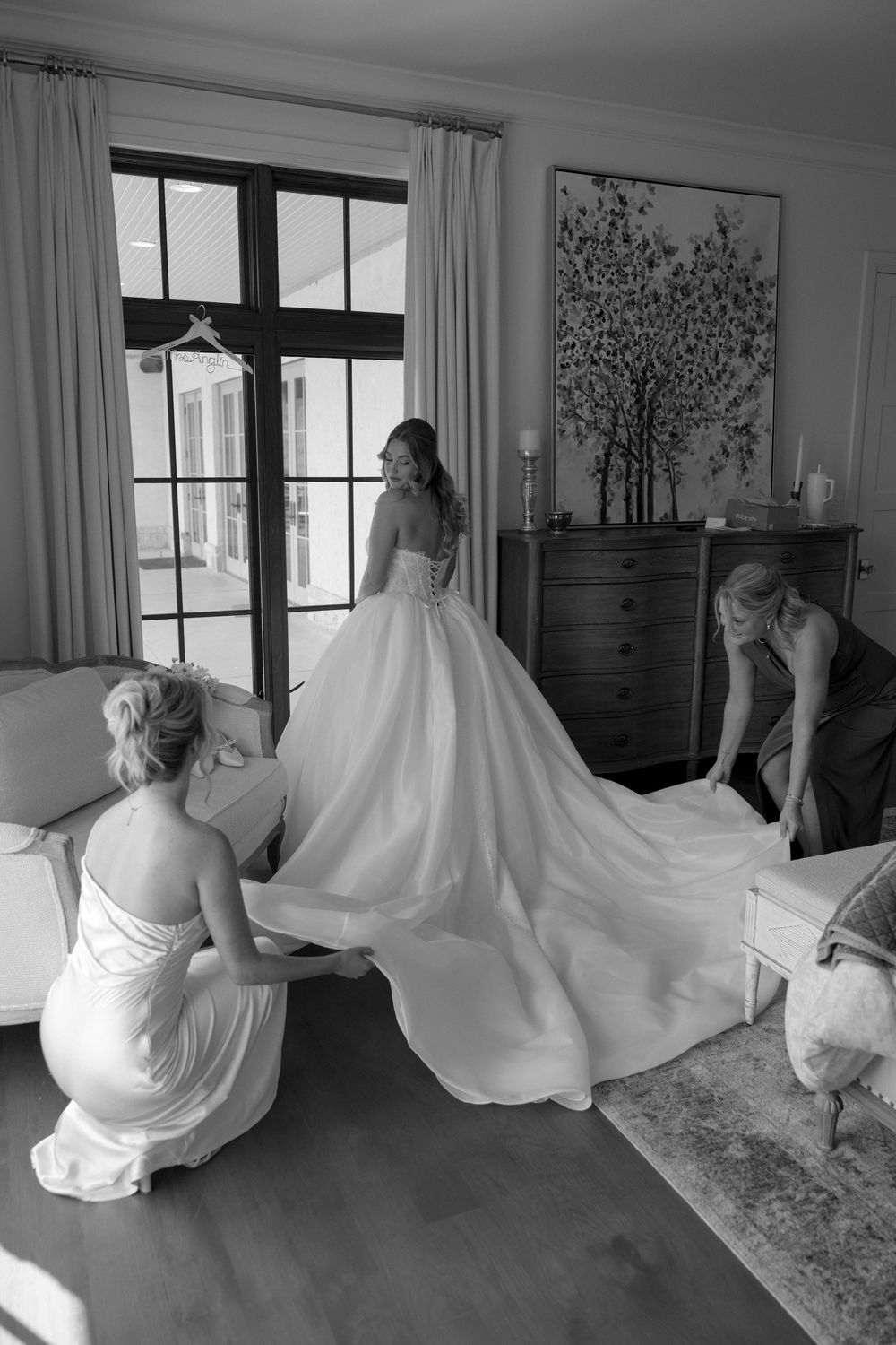 A series of black and white photos showing wedding dress preparations in a sunlit room.