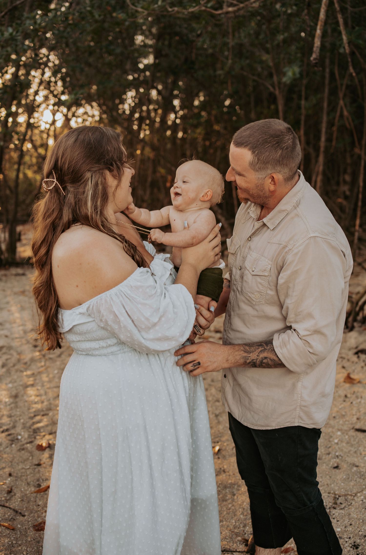 Happy family with baby enjoying golden hour outdoor photo session in natural setting.