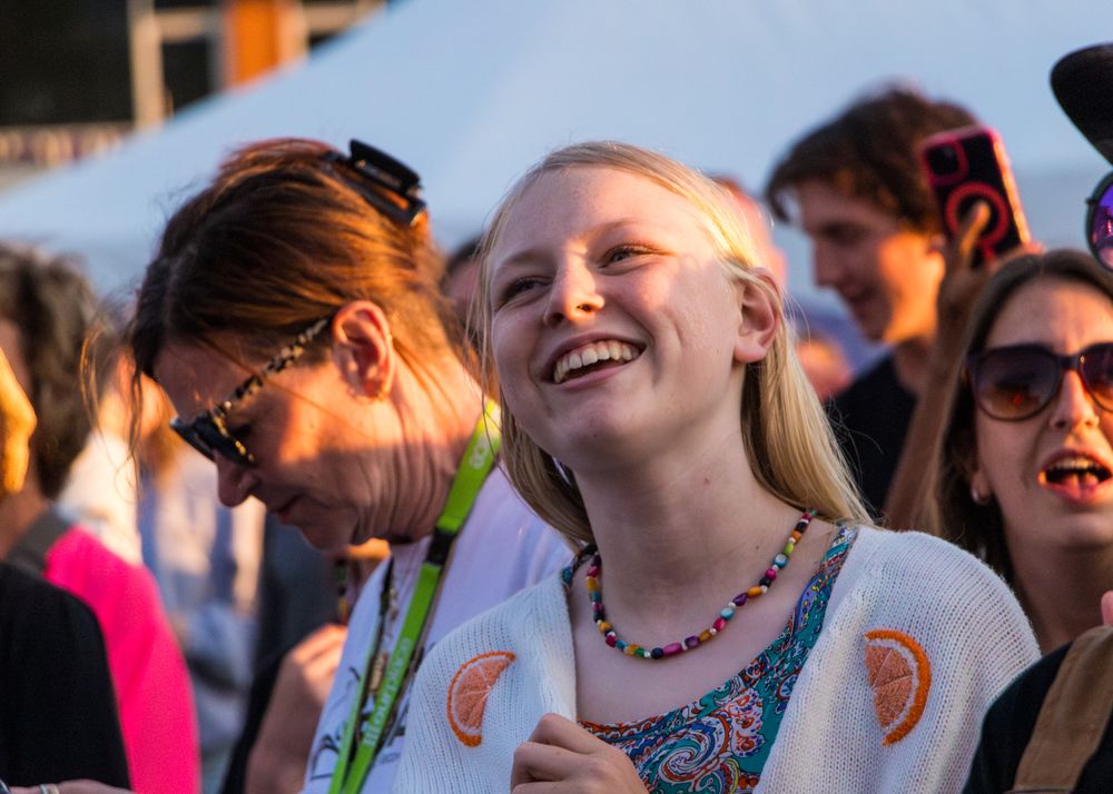 Group of people laughing and enjoying themselves at an outdoor event during golden hour sunset.
