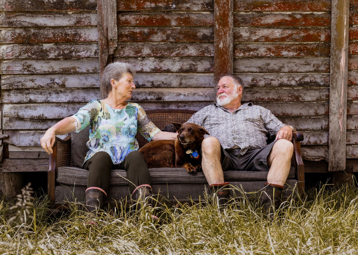 man and lady on a couch with a dog, looking at each other