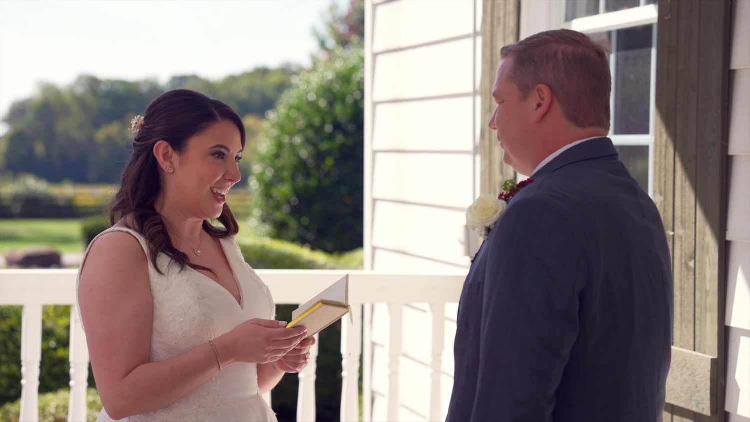 A bride and groom share their first dance at an outdoor wedding reception on a sunny day.