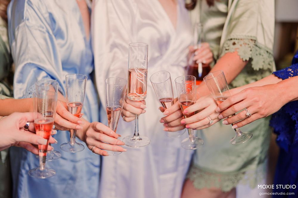 Wedding party members hold champagne glasses in a toast sequence showing multiple hands clinking glasses together.
