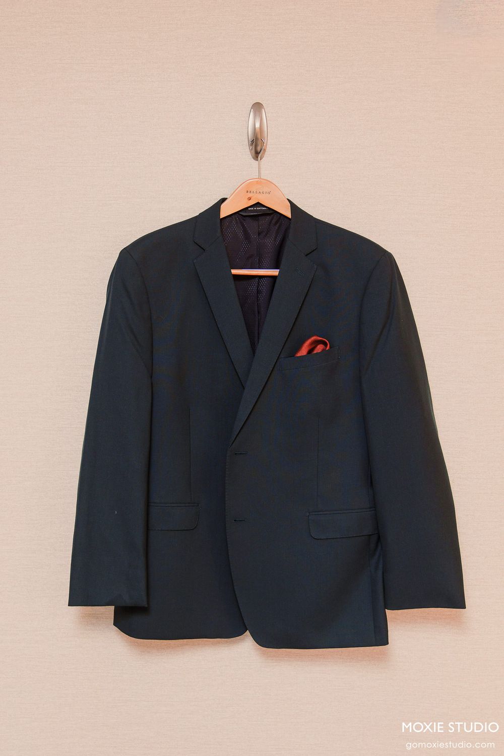 A sequence showing a dark suit jacket displayed on a hanger against a beige wall.