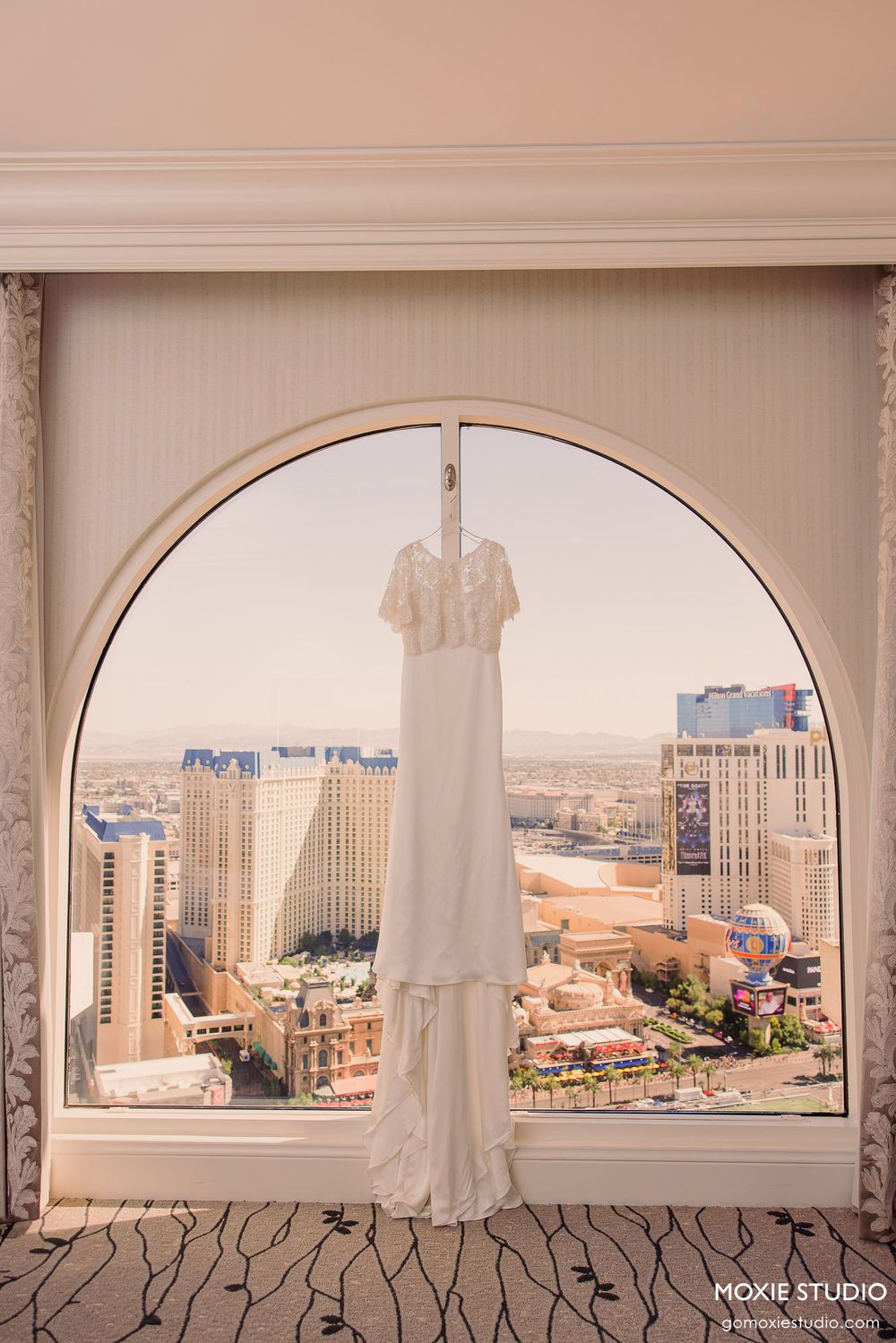 Panoramic view of Las Vegas cityscape through arched windows showing hotels and buildings in warm sunlight.