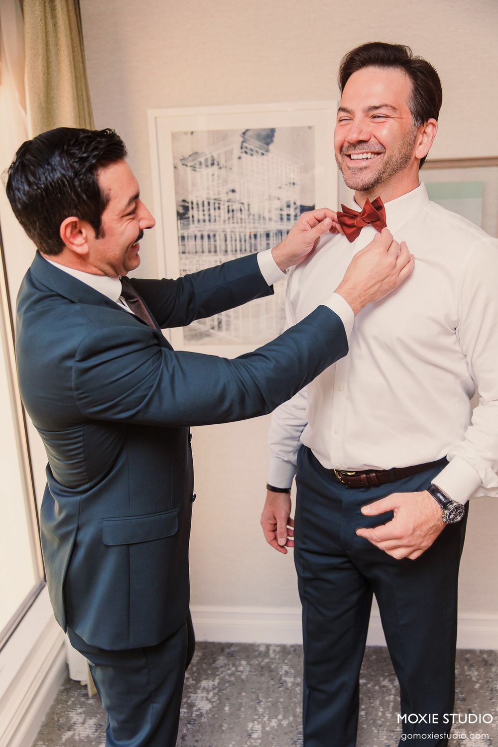 A playful sequence of two people in formal attire sharing a lighthearted moment against a wall with artwork.