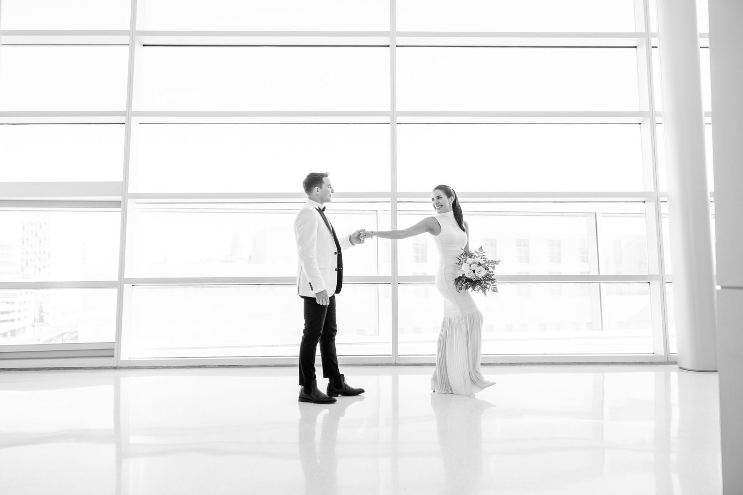 A couple shares a romantic moment in a bright, modern space with floor-to-ceiling windows.