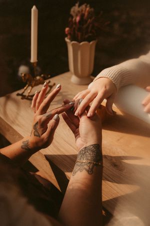Close-up sequence of tattooed hands writing with a pen on paper in warm, moody lighting.