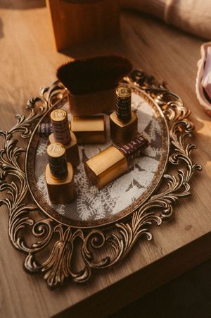 Vintage ornate brass mirror tray with perfume bottles and accessories arranged in moody lighting on wooden surface.