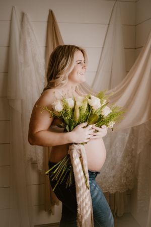 Artistic portrait series showing a person in white holding a bouquet of cream roses against a light fabric backdrop.
