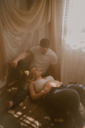 Two people sit together in a dimly lit room playing card games on a couch.