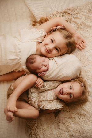 A tender moment captured in sepia tones showing affectionate embraces on soft bedding with delicate lace details.