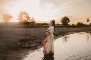 A person in a white dress walks along a serene beach at sunset creating a dreamy silhouette against the golden sky.