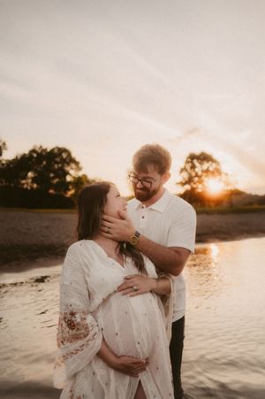 A romantic couple embraces on a beach at sunset, silhouetted against the golden sky and water.