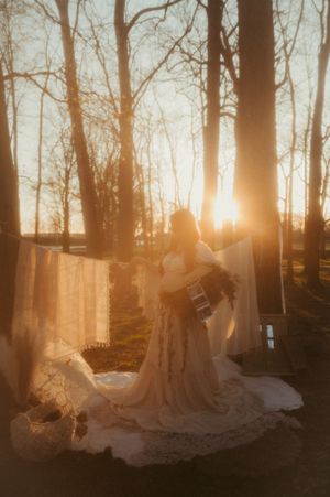 A dreamy sunset wedding photoshoot in a forest with silhouetted trees and flowing white dress in golden light.