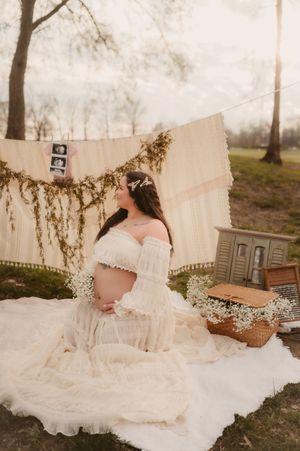 A dreamy outdoor boudoir photo session features a flowing white dress and delicate baby's breath flowers in a natural setting.