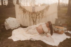 A romantic bride in a flowing white lace gown poses in a rustic outdoor setting during golden hour.