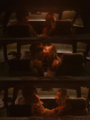 Dark silhouettes of people inside cars at night illuminated by warm orange lighting.