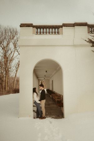 A series of white arched walkways and columns in a minimalist architectural style against a winter landscape.