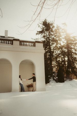A series of snowy winter scenes showing a person walking through white arched doorways at sunset.