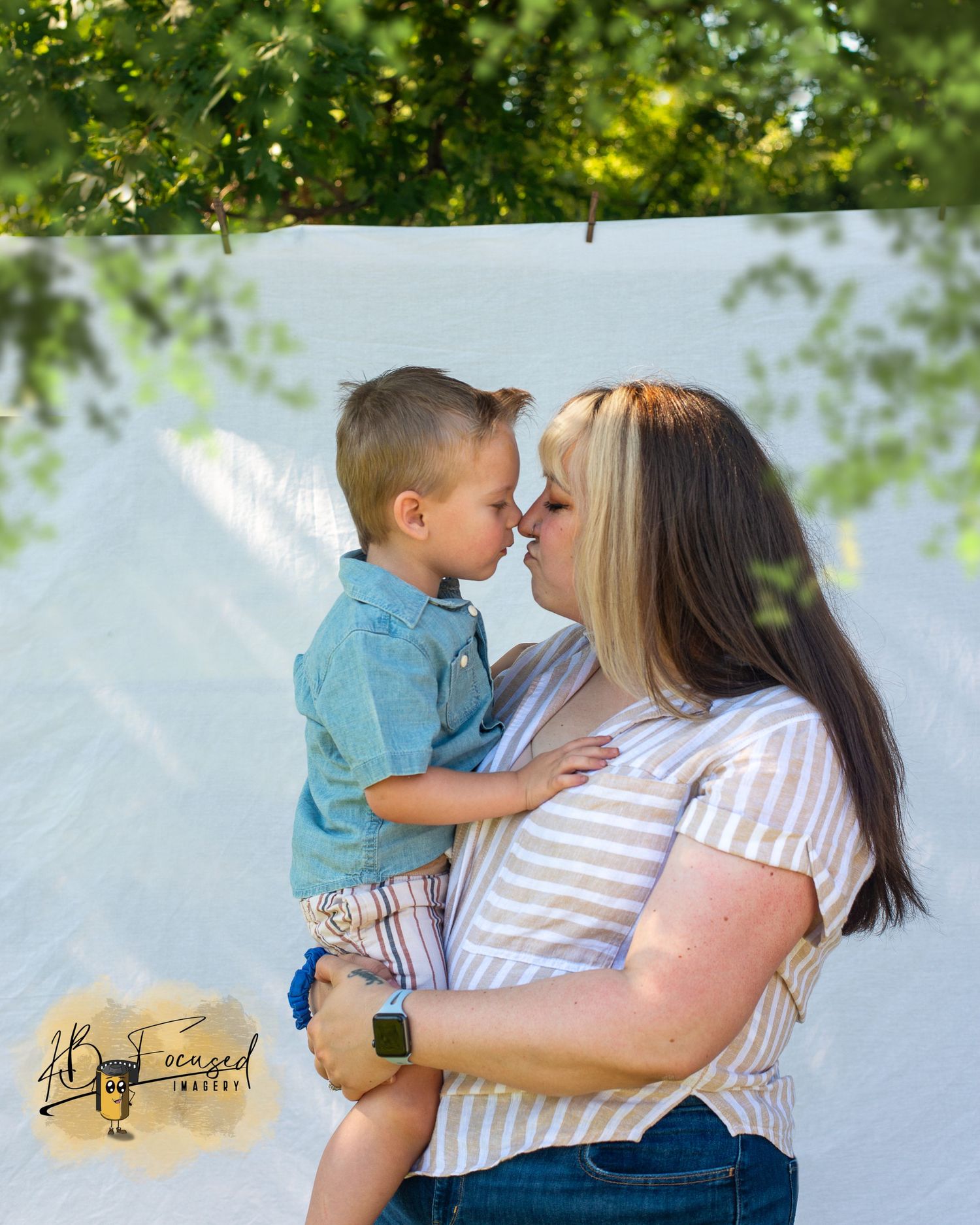 Mother and child sharing a tender moment outdoors under green trees.