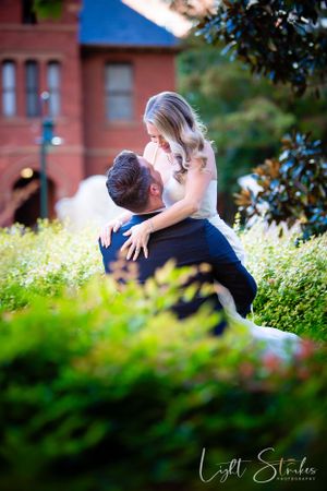 A romantic outdoor engagement photo shoot with a couple embracing in a lush garden setting captured by wedding photographer in Charlotte.