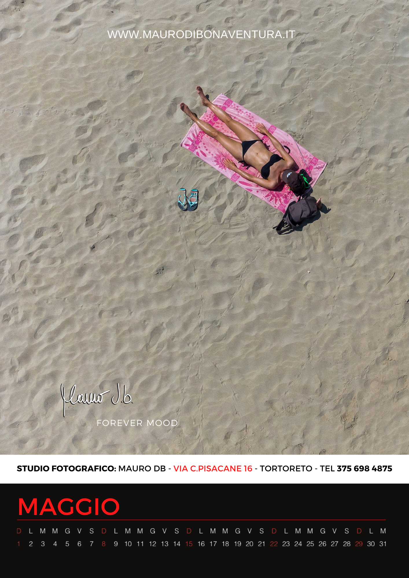 Aerial view of someone lounging on a pink beach towel with a butterfly shadow on sand.