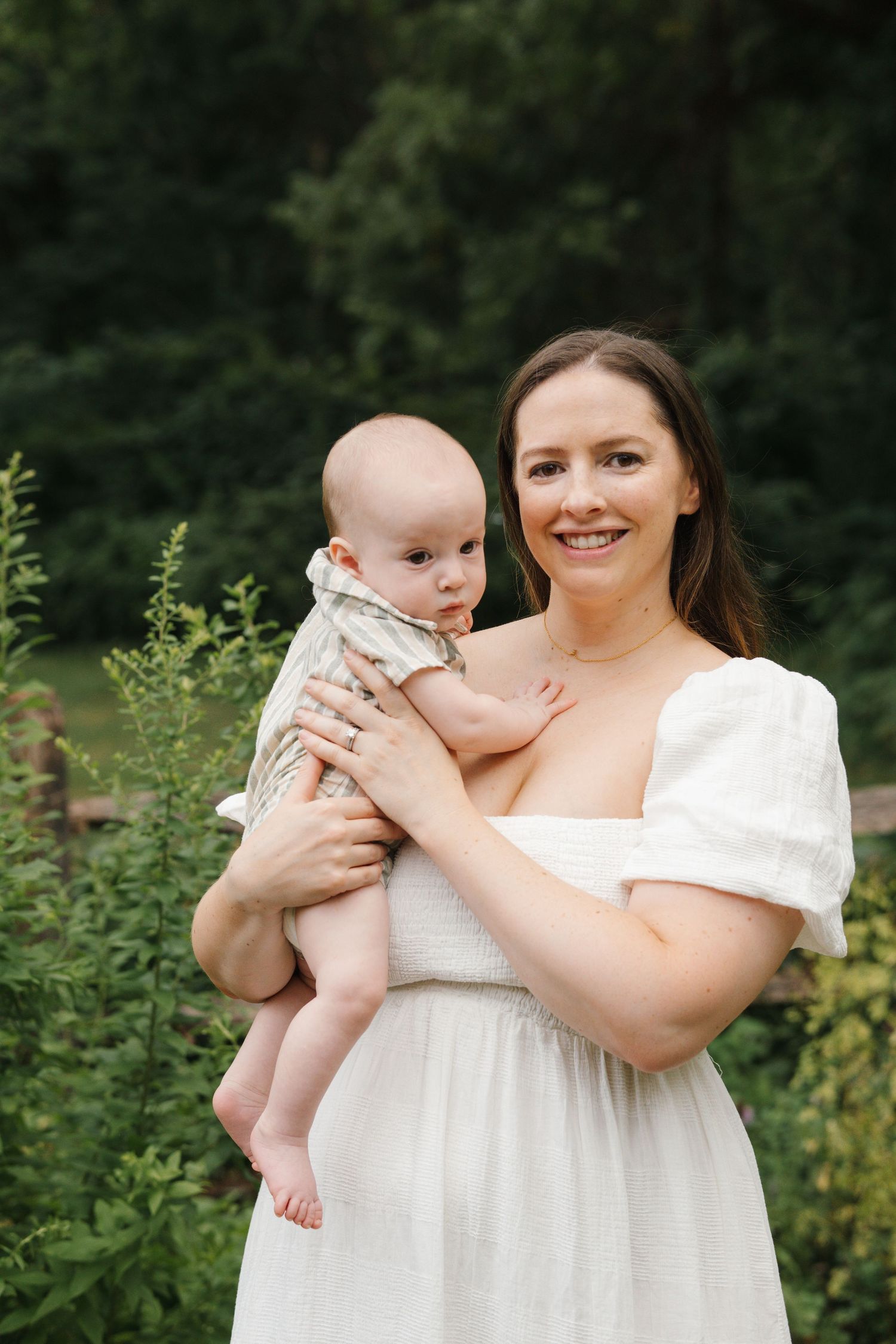 Mother holding her baby in a colorful herb and wildflower garden at Barclay Farmstead, for a family photoshoot in Cherry Hill, NJ.