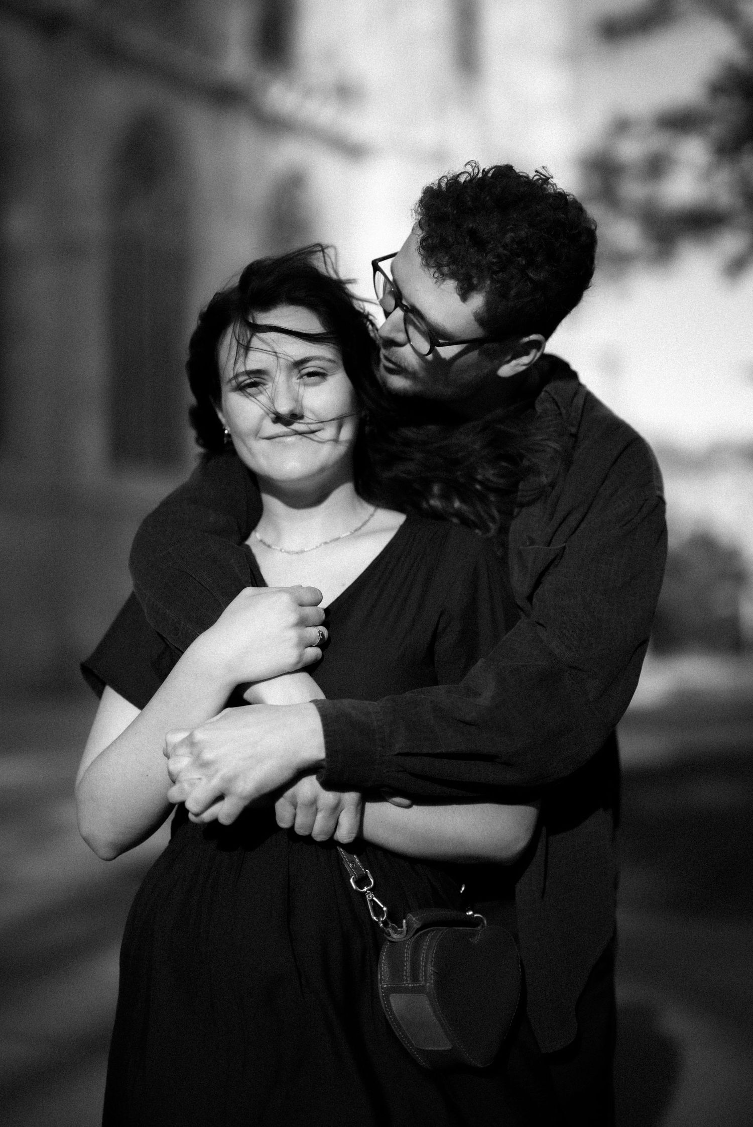 Black and white photo of embracing couple showing affection in an urban setting.