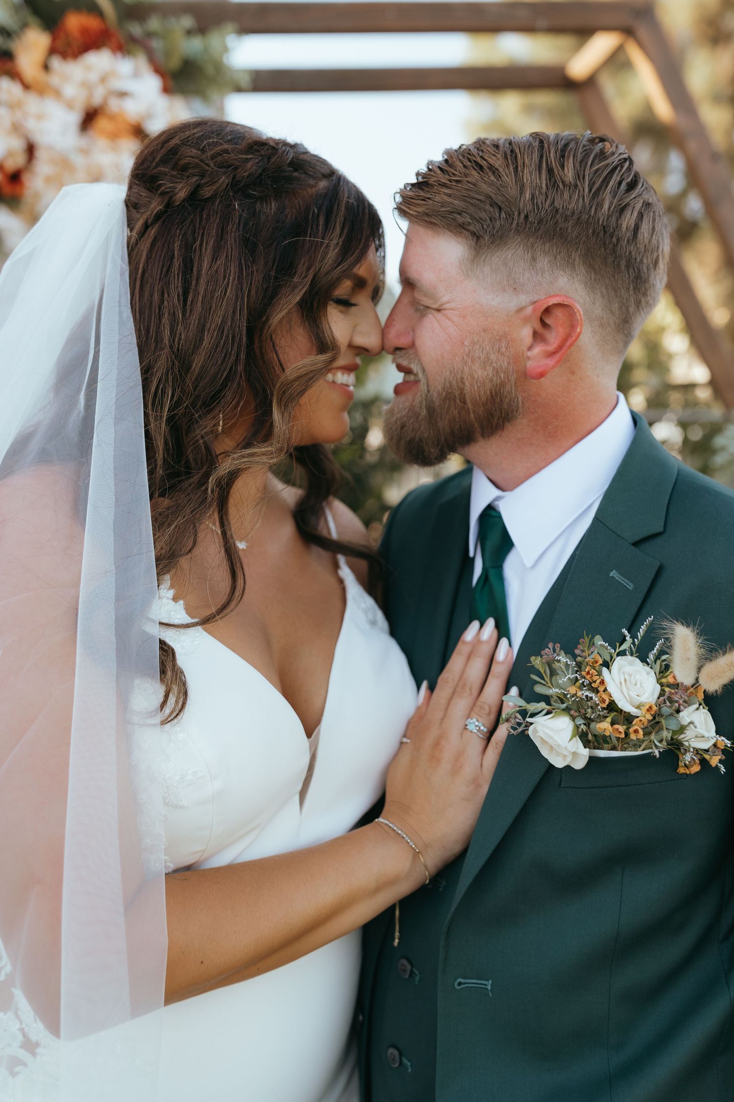 couple in wedding attire facing each other, nose to nose, eyes closed and smiling.