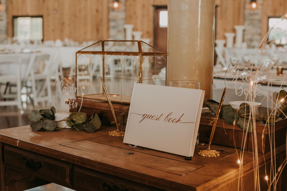 Wooden guest book table with glass terrarium and calligraphy sign at wedding reception.