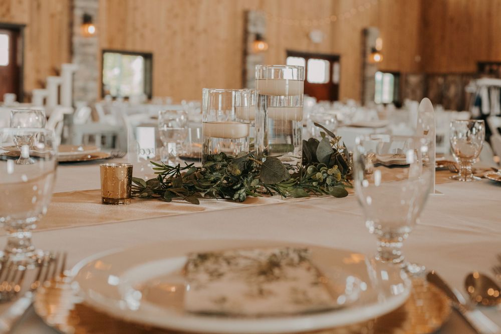 Elegant wedding table setting with glass candle holders and eucalyptus centerpiece.