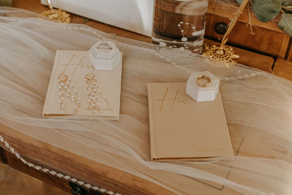 Wedding stationery and hexagonal ring boxes displayed on flowing fabric.
