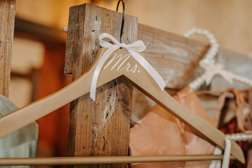 White wooden hanger with ribbon bow against rustic wooden background.