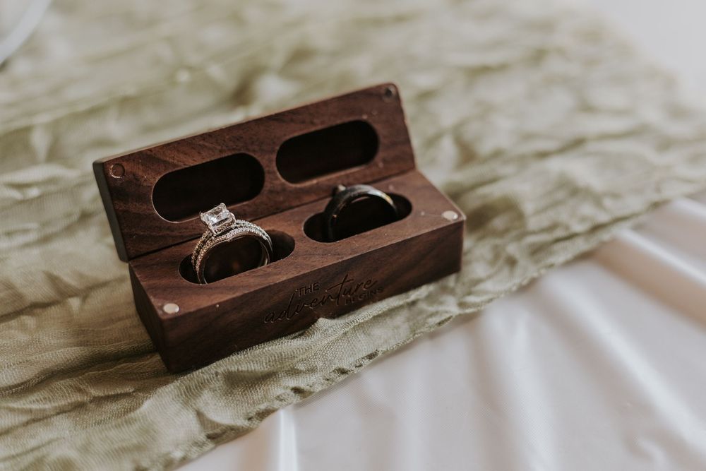 A wooden engagement ring box shown from multiple angles on a white marble surface.