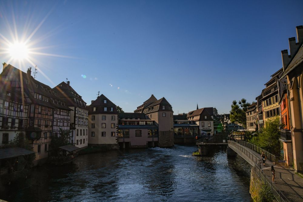 Scenic view of Strasbourg Petite France district with colorful historic buildings along the river at golden hour.