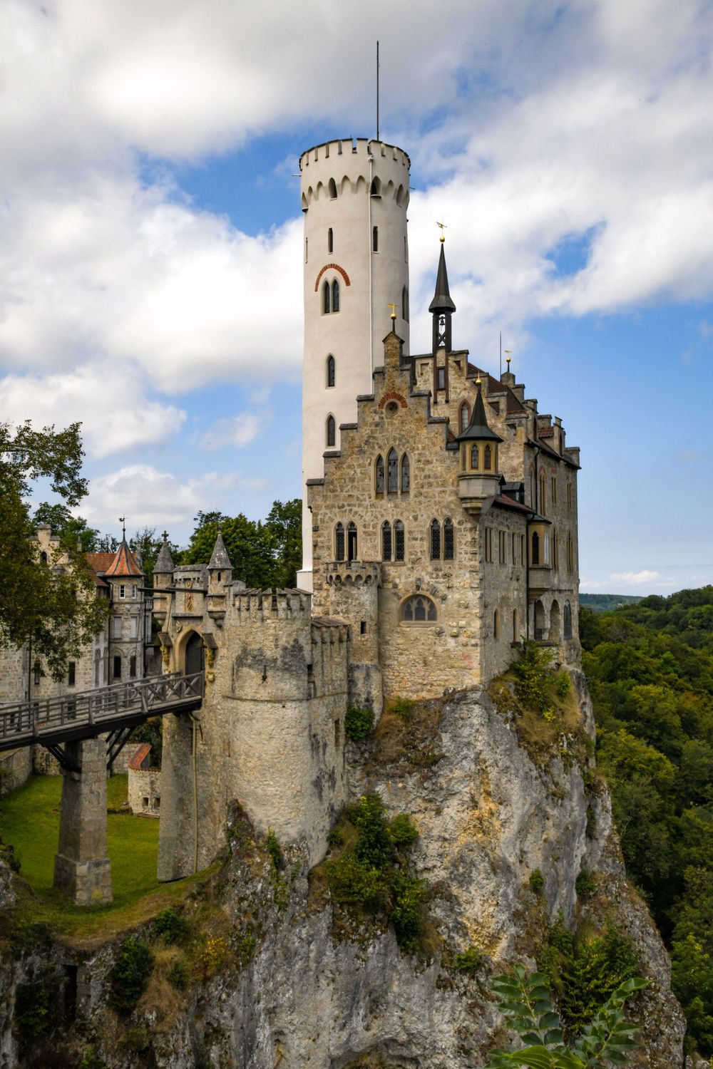 Lichtenstein Castle perched dramatically on a rocky cliff in Baden-Württemberg, Germany, surrounded by lush green forest.