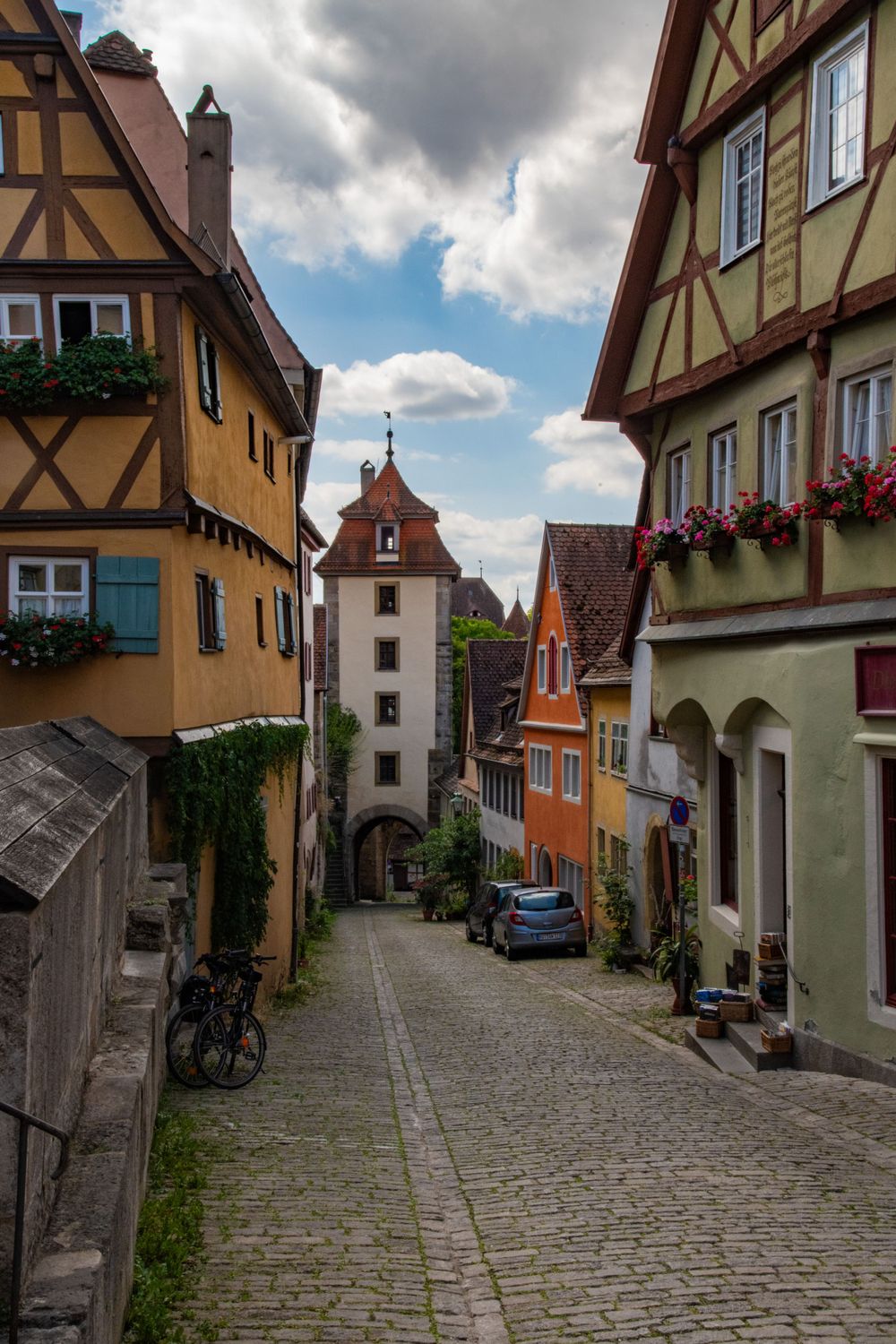 Charming cobblestone alley in Rothenburg ob der Tauber lined with colorful half-timbered medieval buildings.