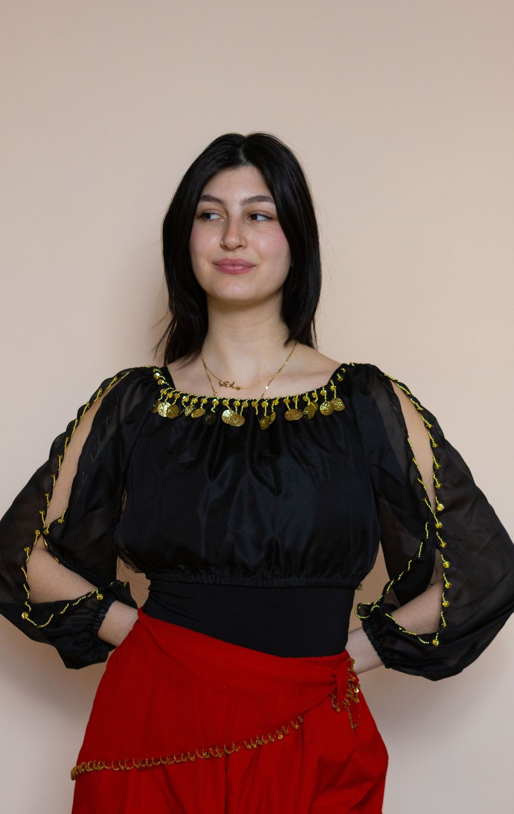 Model poses in black peasant top with gold trim and red skirt.