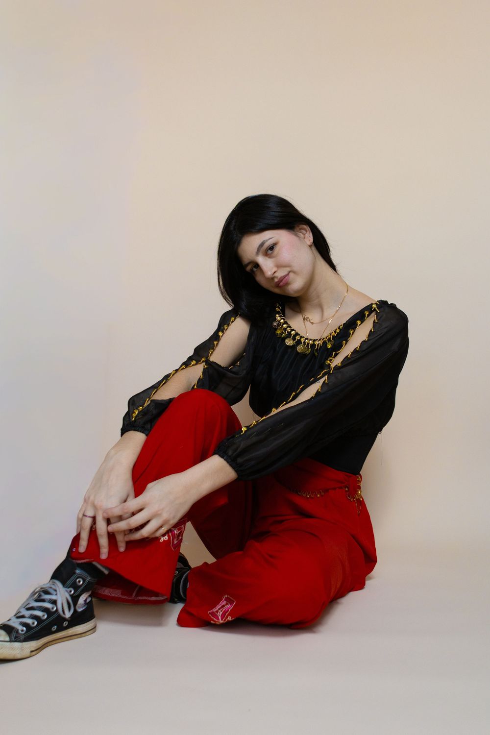 Model in black and red outfit poses artistically on floor.