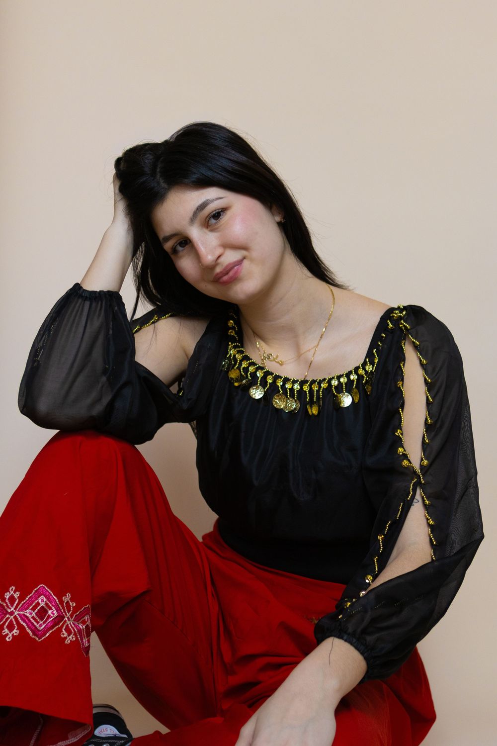 Model in vintage-inspired black and red outfit with gold embellishments poses dramatically.